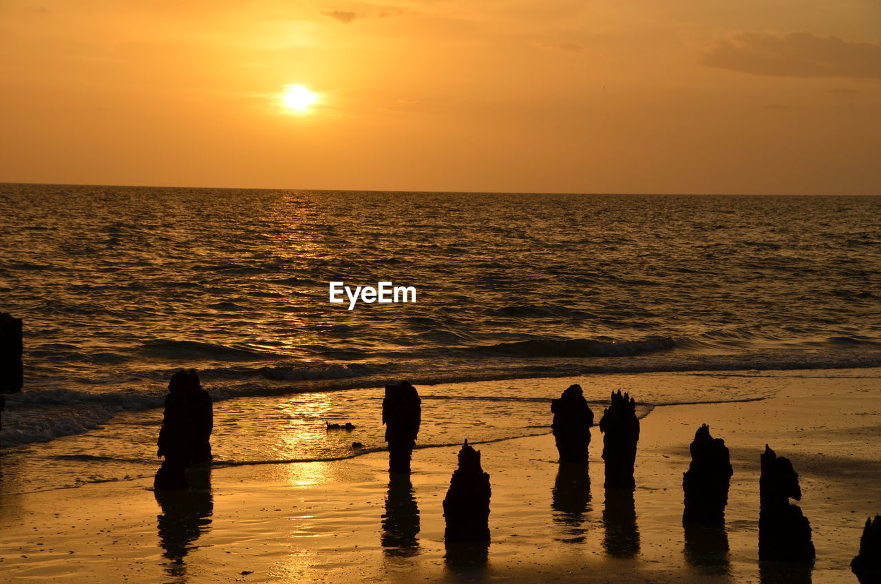 Silhouette rocks at beach against sky during sunset