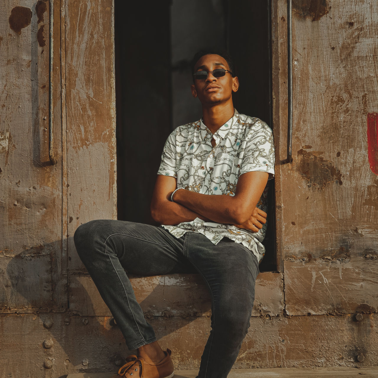 Portrait of young man sitting against abandoned train trailer 