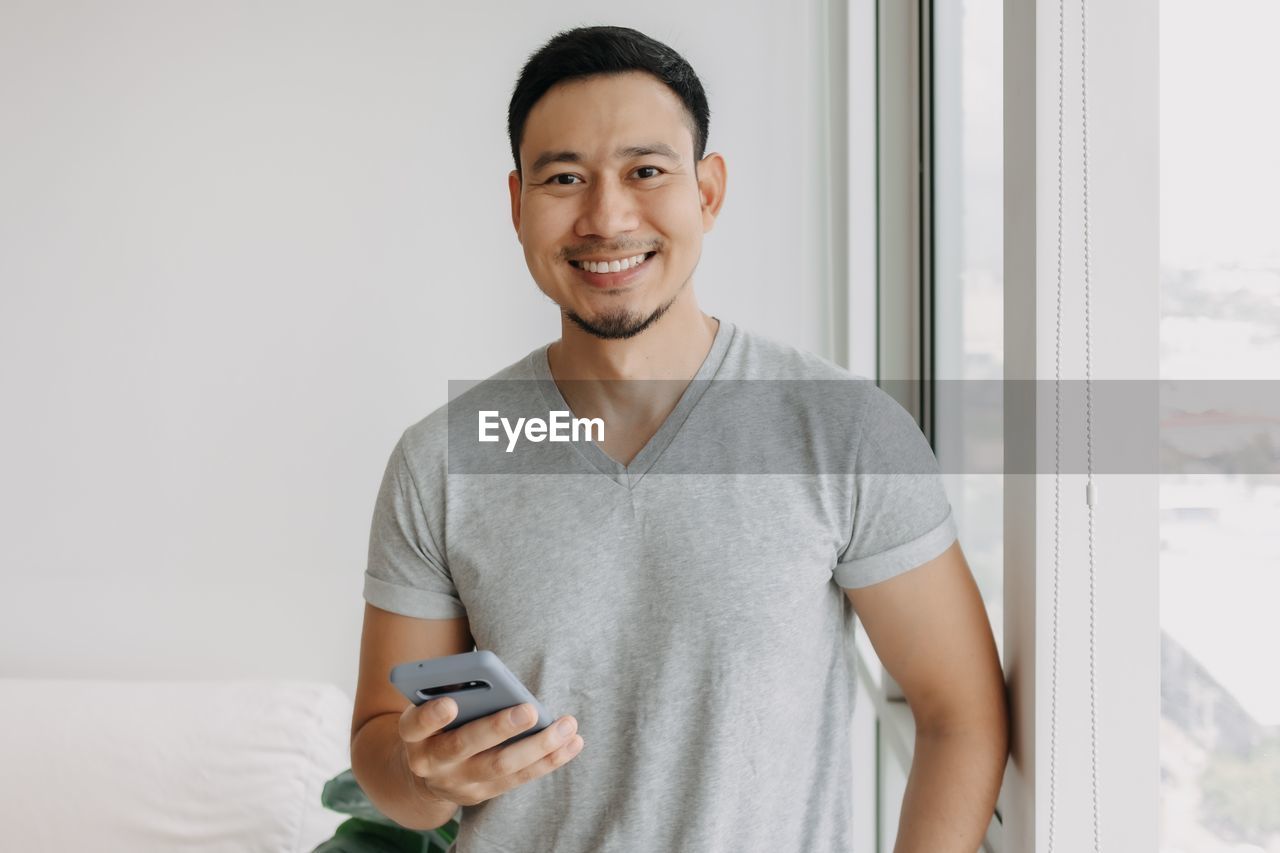 portrait of young man using mobile phone at home