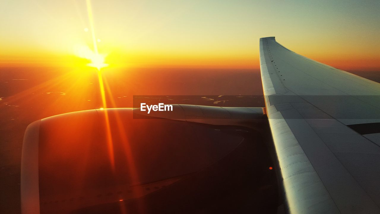 Cropped image of airplane flying against sky during sunset