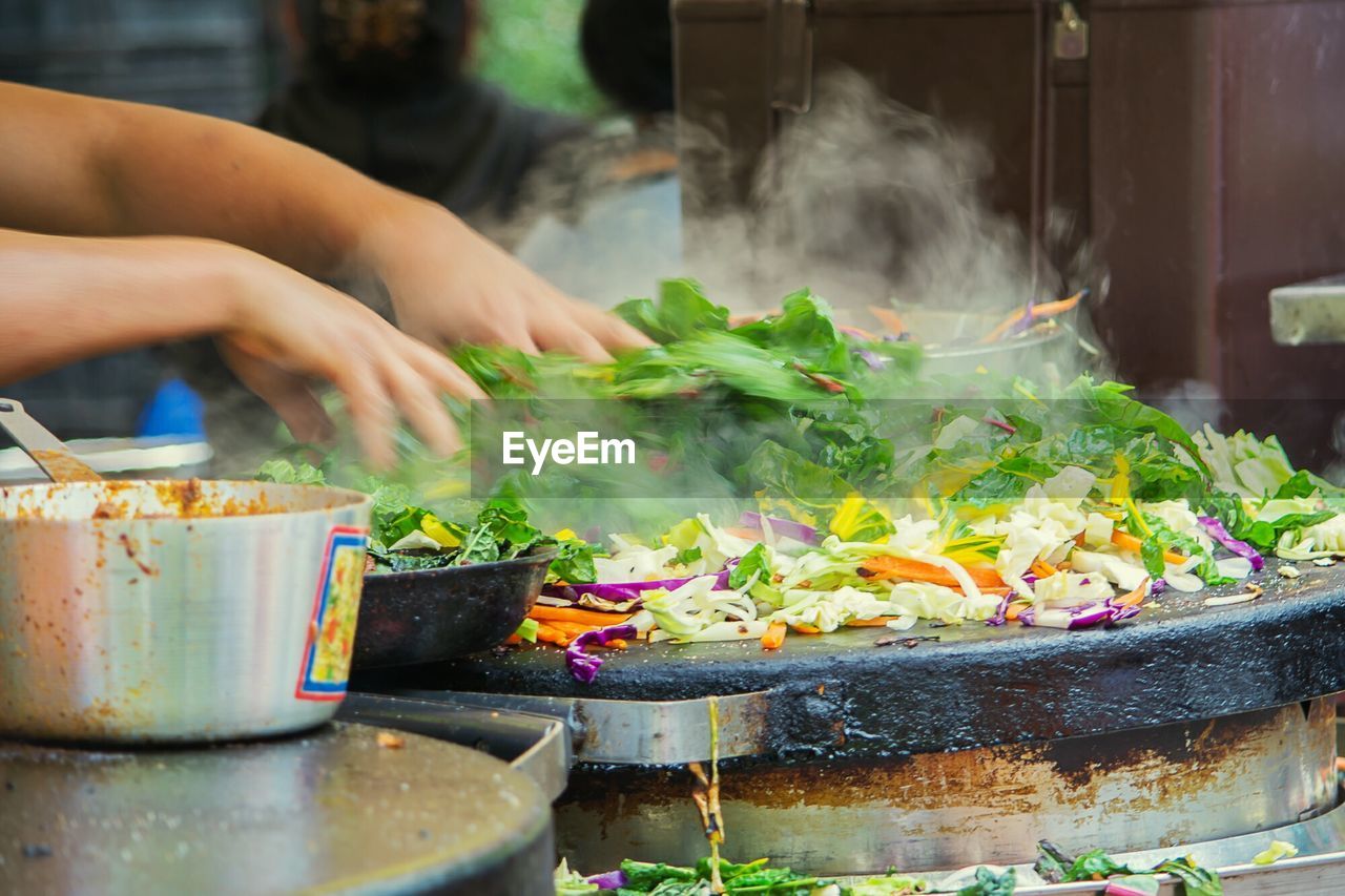 Cropped image of vendor hand cooking vegetables in market