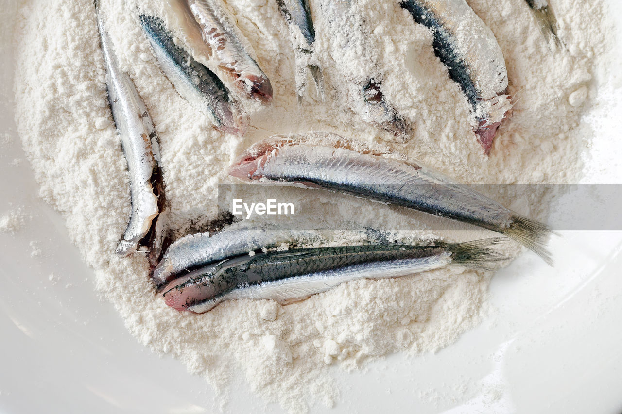 Overhead view of raw fish with flour in plate