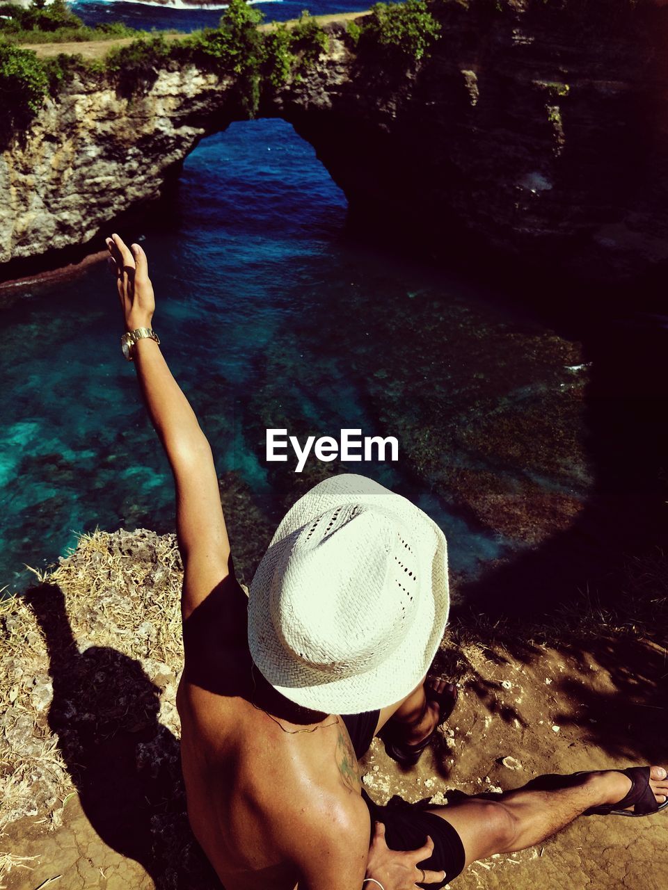 High angle view of man wearing hat on rock in sea