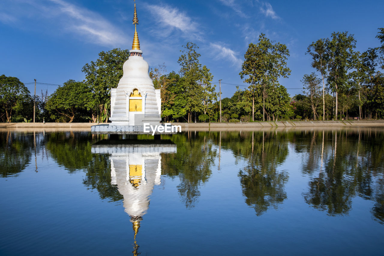 reflection, water, religion, architecture, sky, lake, travel destinations, built structure, nature, belief, tree, travel, plant, spirituality, blue, building, no people, temple - building, history, place of worship, tourism, building exterior, the past, pagoda, tranquility, cloud, outdoors, landscape, reflecting pool, environment, beauty in nature, gold, scenics - nature, city, culture, reflection lake, business finance and industry