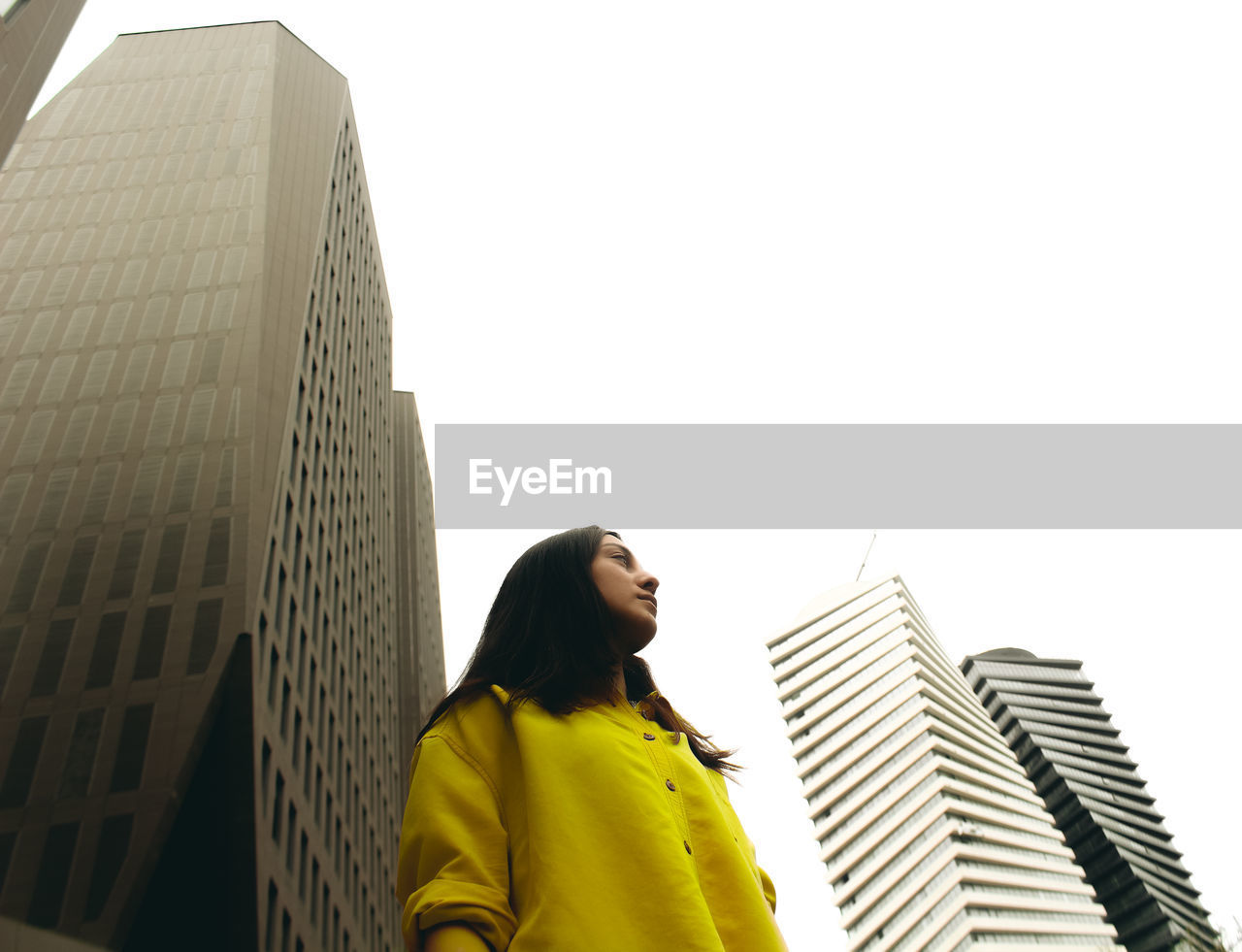 Low angle view of woman standing against modern buildings