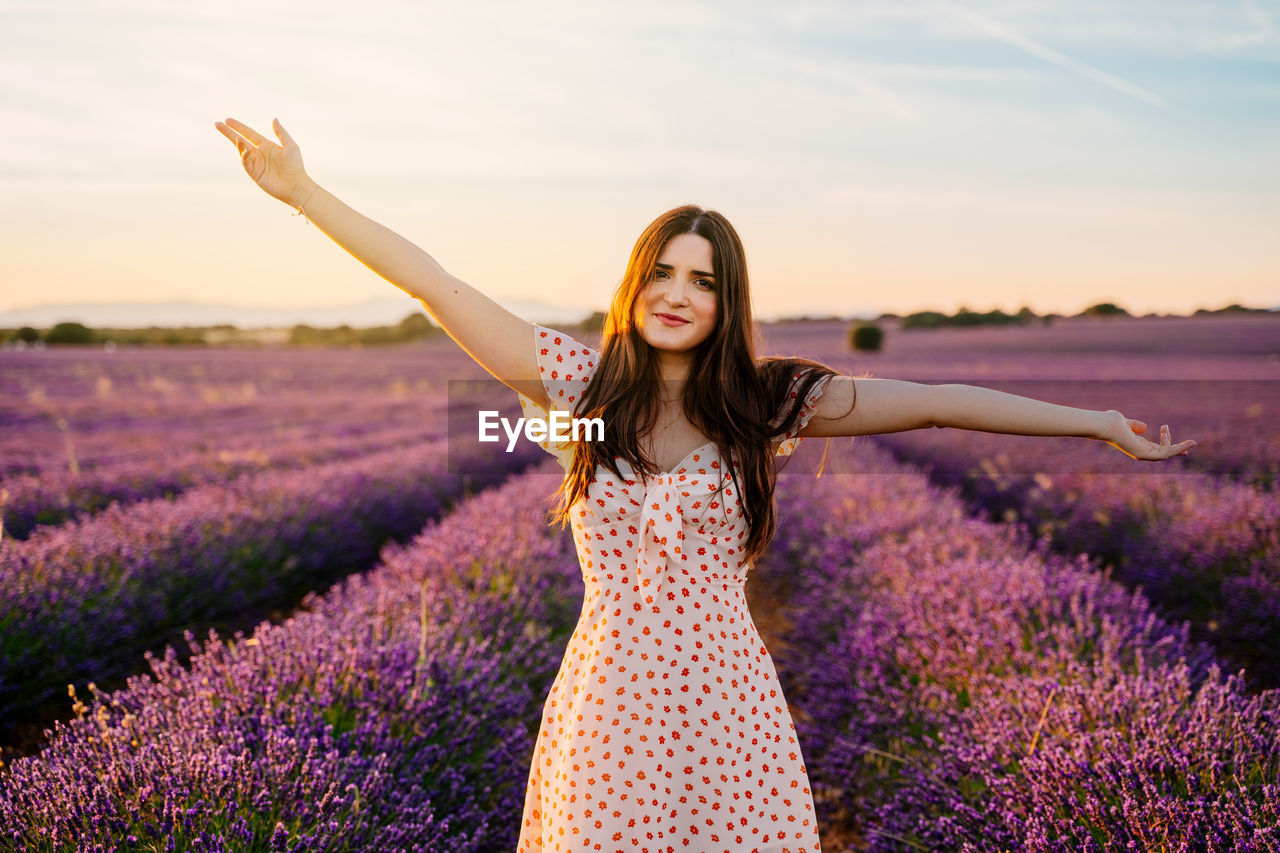 Portrait of woman with arms outstretched standing on lavender field
