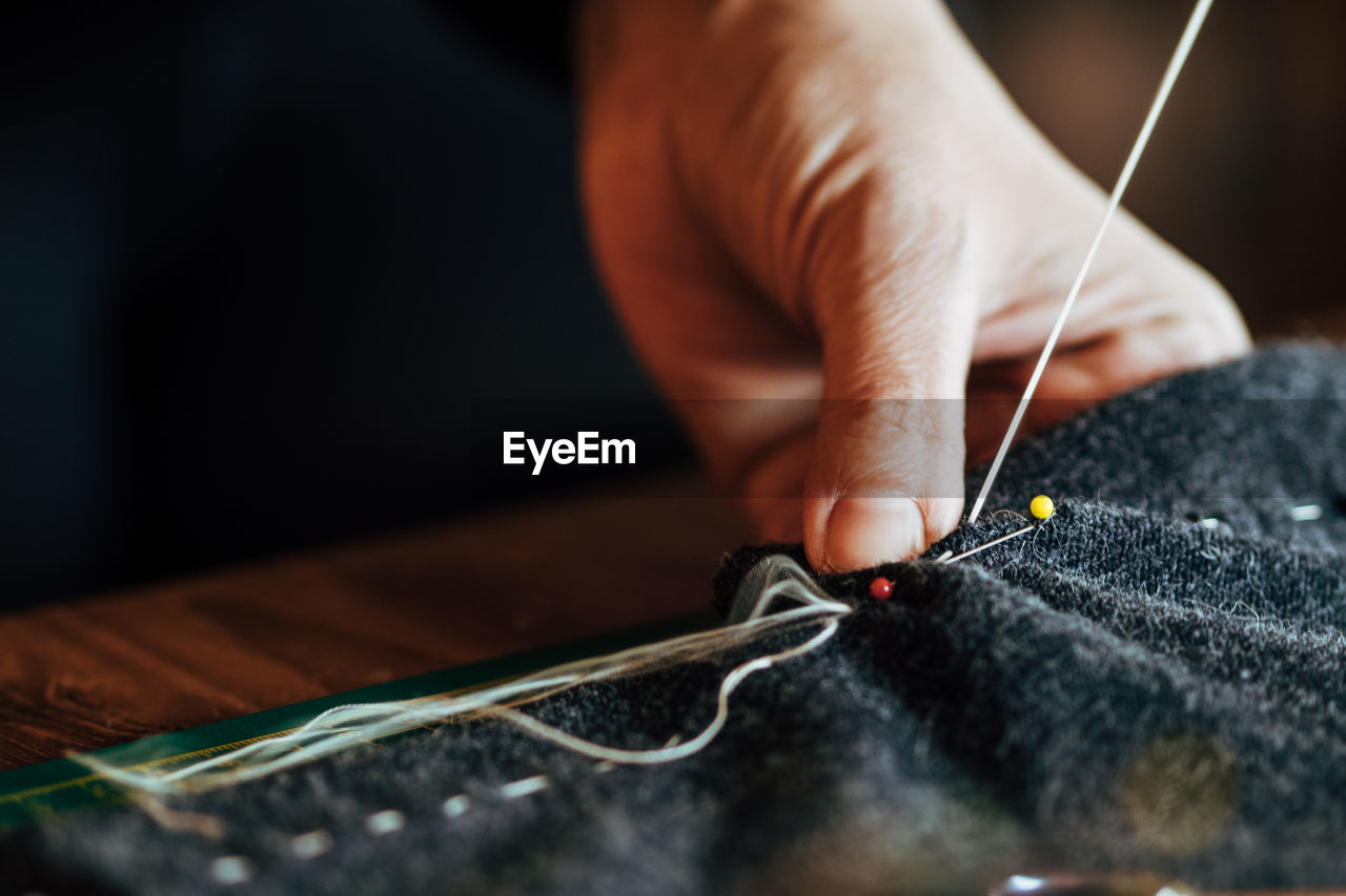 Close-up of cropped hand sewing textile in workshop