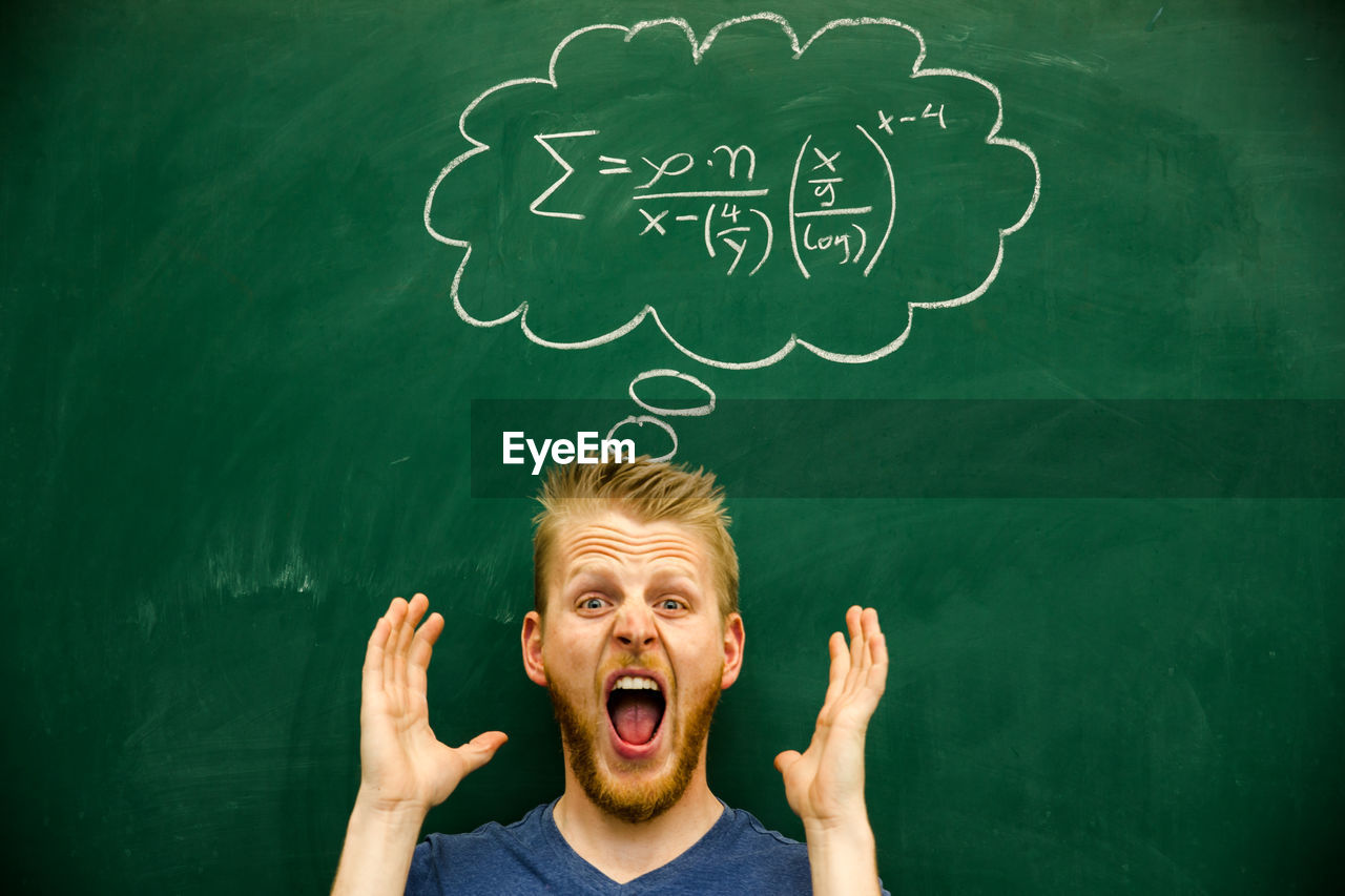 Man gesturing with mathematical formula on blackboard