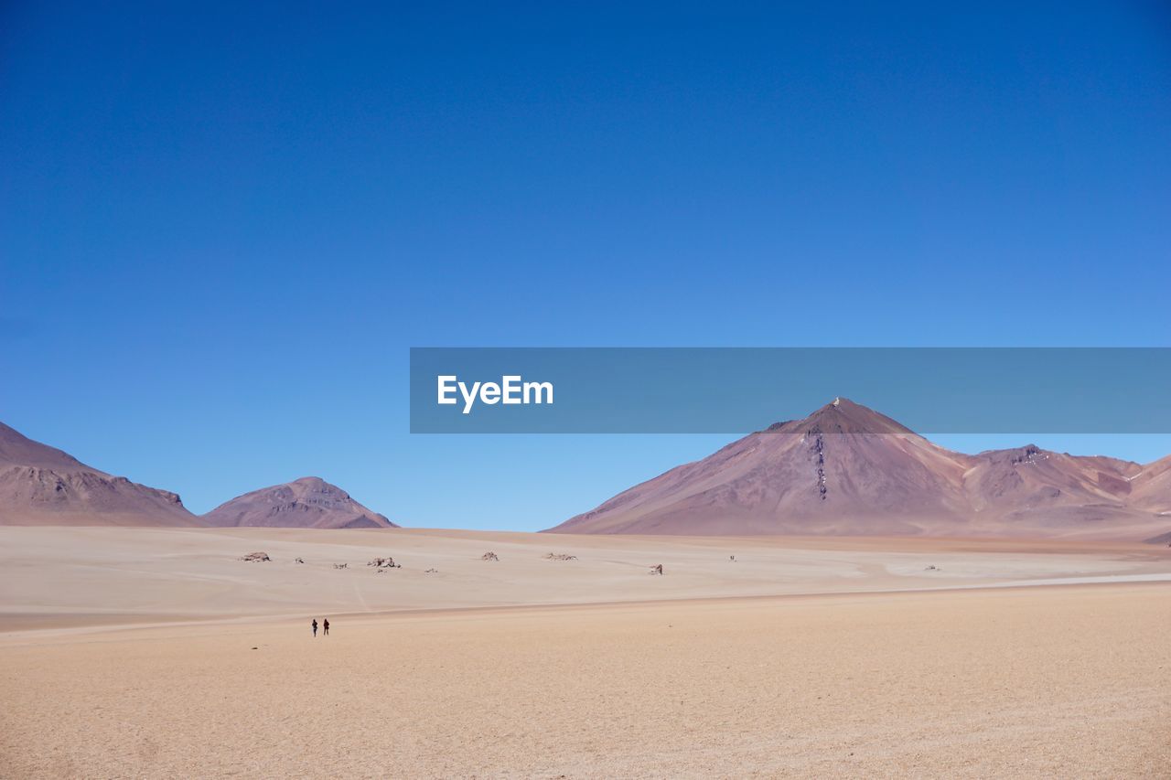 Scenic view of desert against clear blue sky