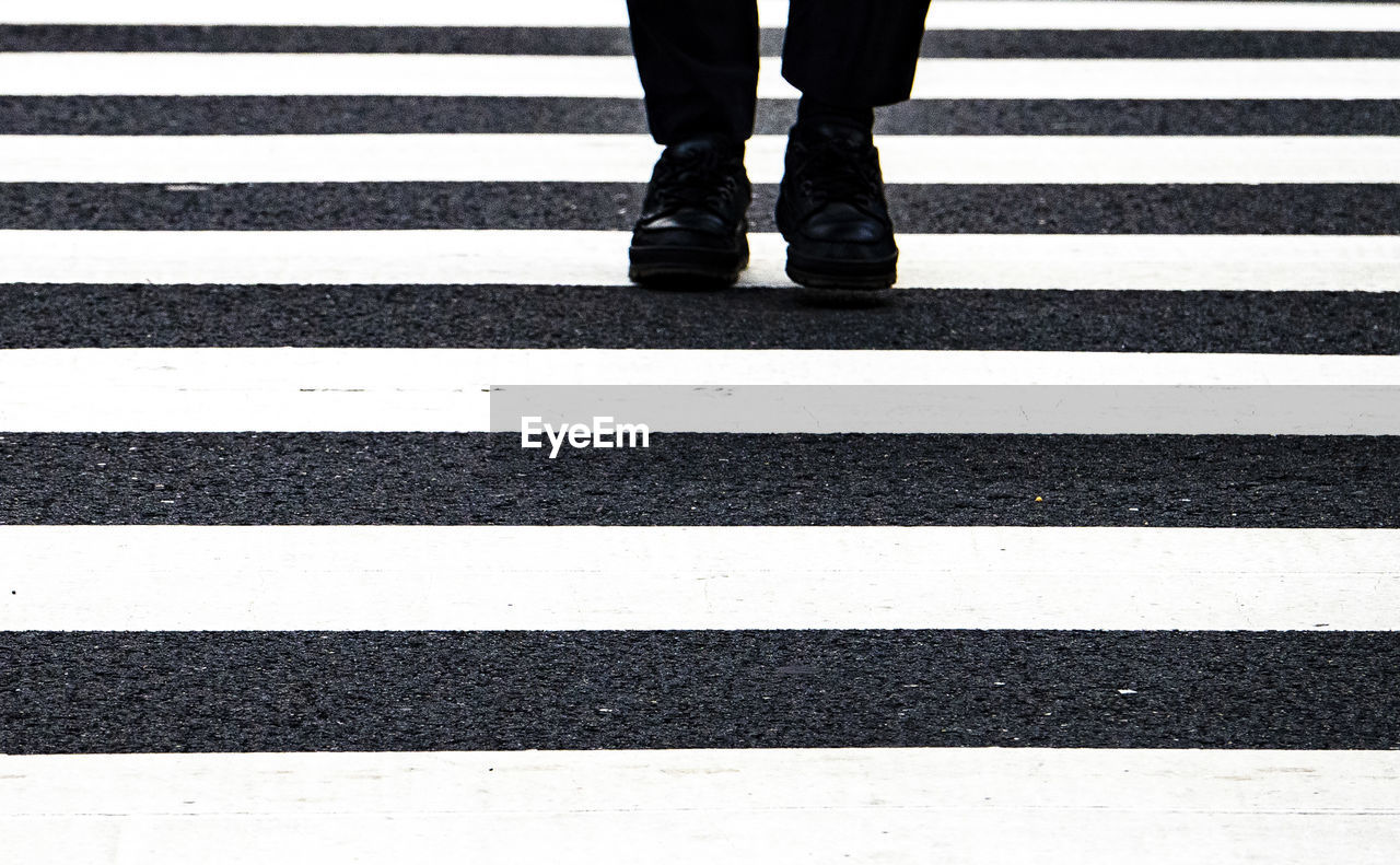 LOW SECTION OF MAN STANDING ON ZEBRA CROSSING ROAD