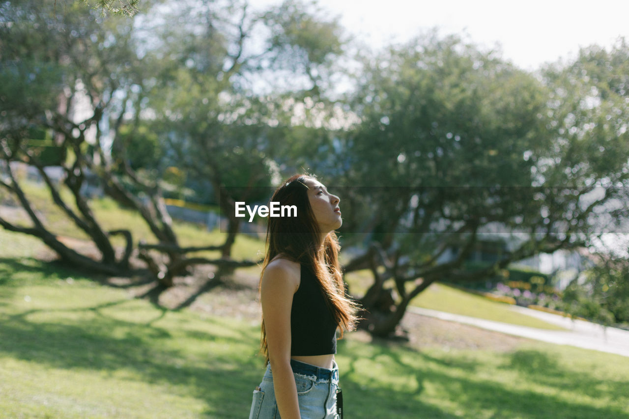 Woman looking away while standing at park