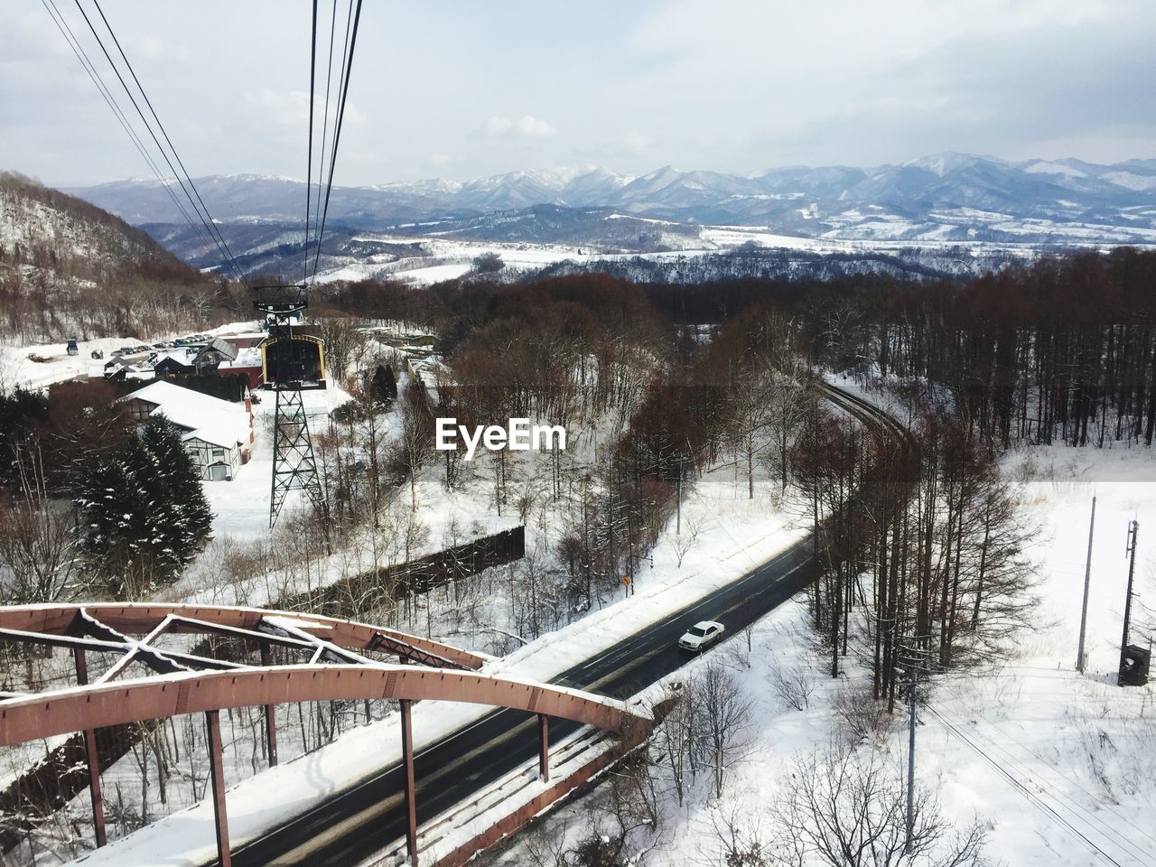 BRIDGE OVER SNOW COVERED MOUNTAIN AGAINST SKY