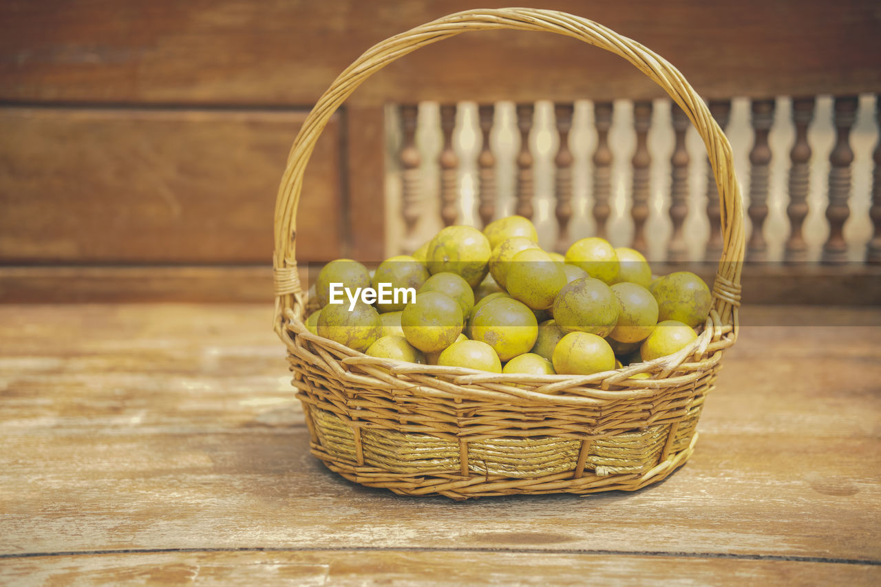 Fresh orange tangerine fruit in rattan wicker basket on wooden chair