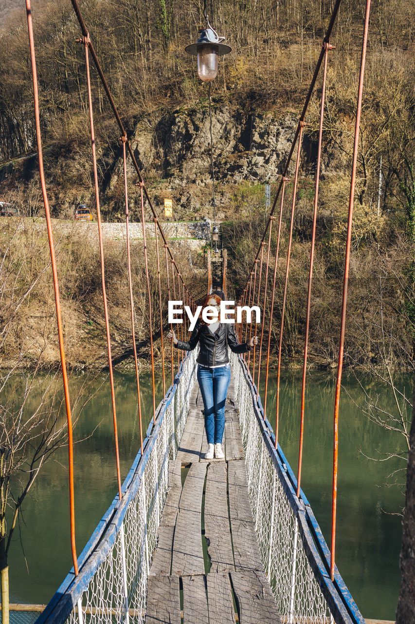 Woman standing on footbridge over river