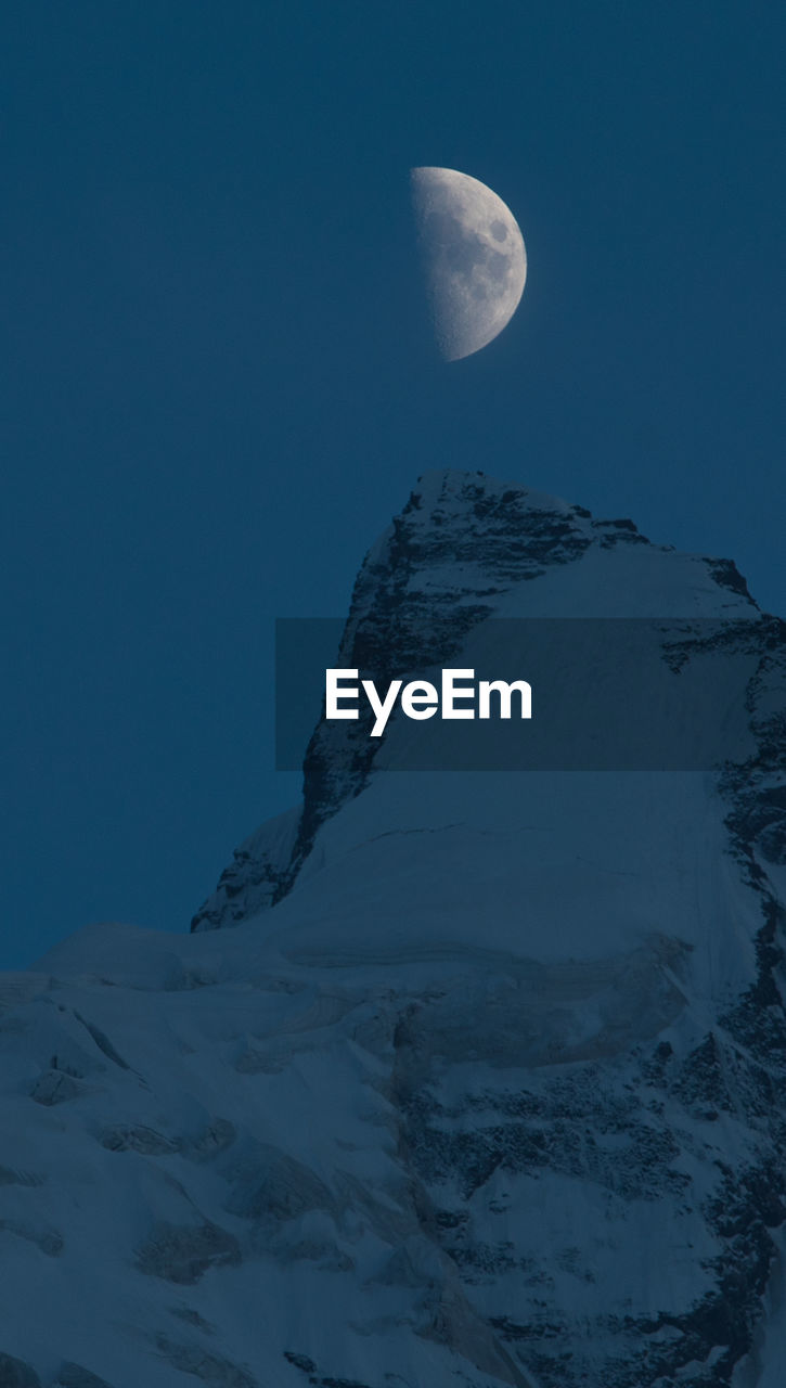 LOW ANGLE VIEW OF SNOWCAPPED MOUNTAINS AT NIGHT