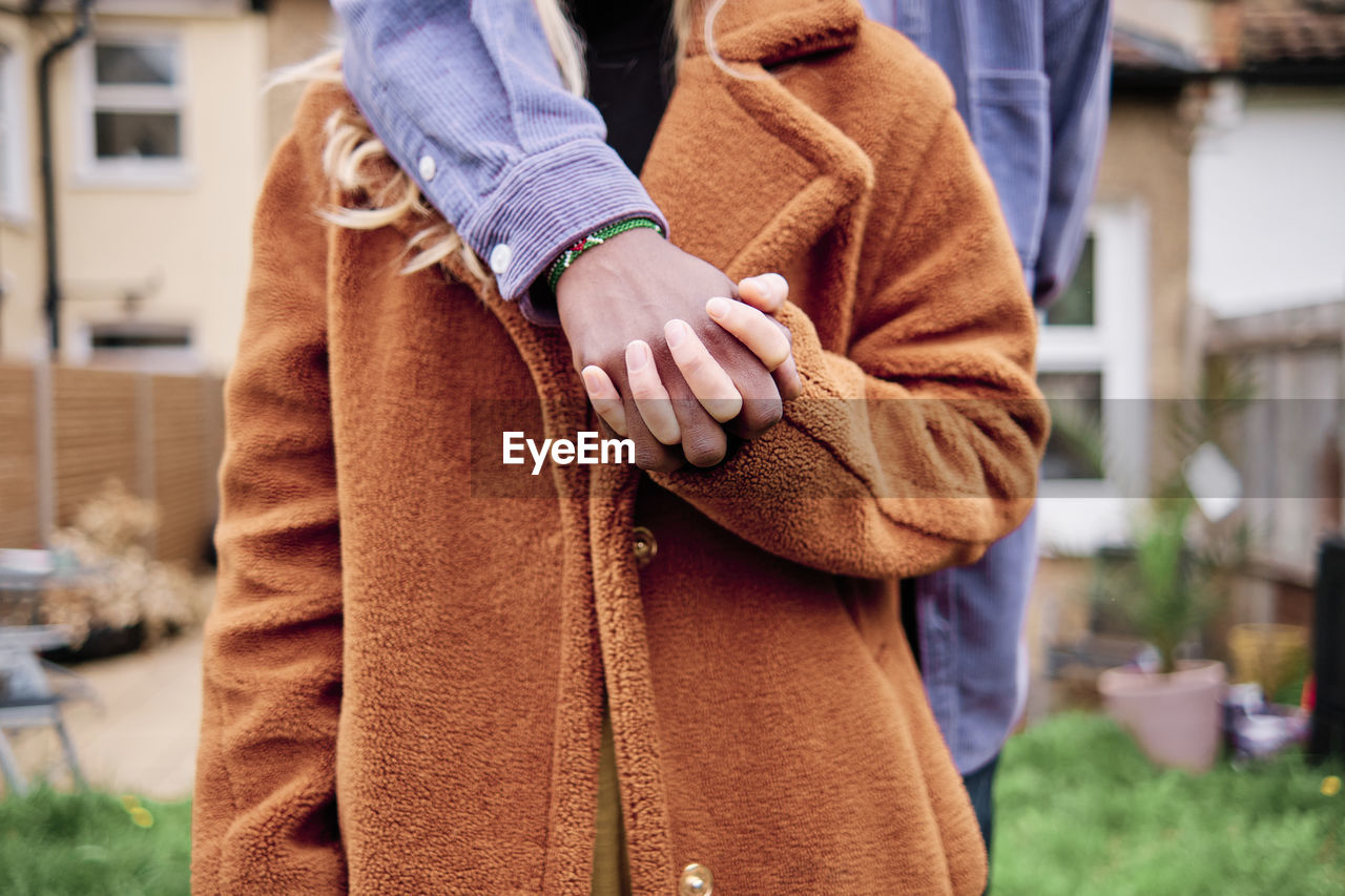 Young couple holding hands while standing at backyard