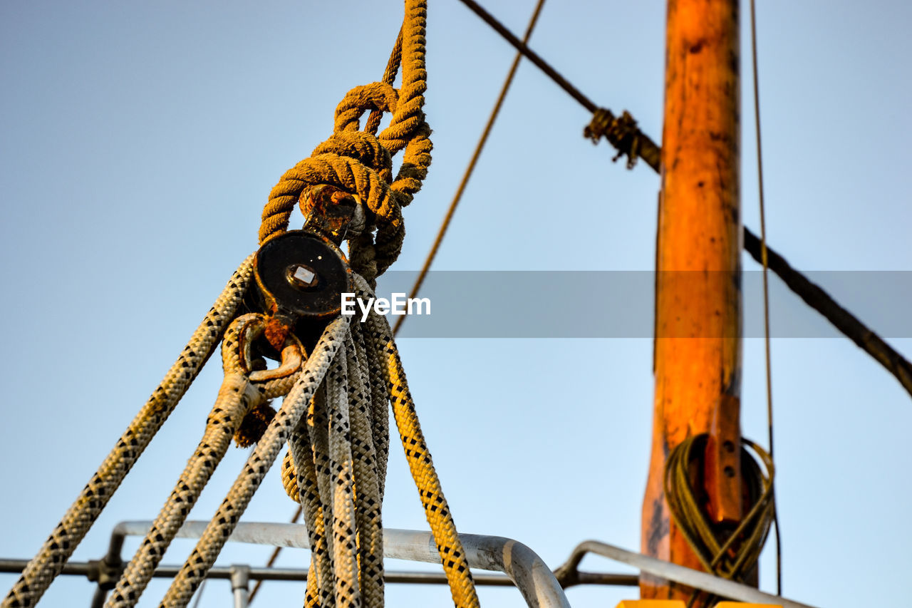 LOW ANGLE VIEW OF ROPES TIED UP AGAINST SKY