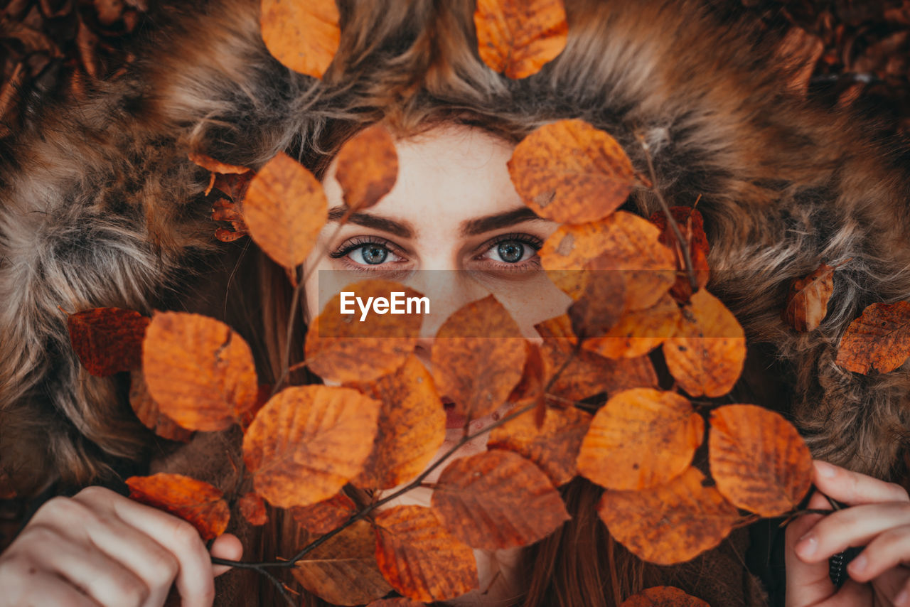 CLOSE-UP PORTRAIT OF PERSON HOLDING AUTUMN LEAVES