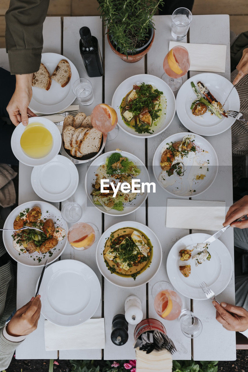 Directly above shot of male and female senior friends having food along with drinks on table at restaurant