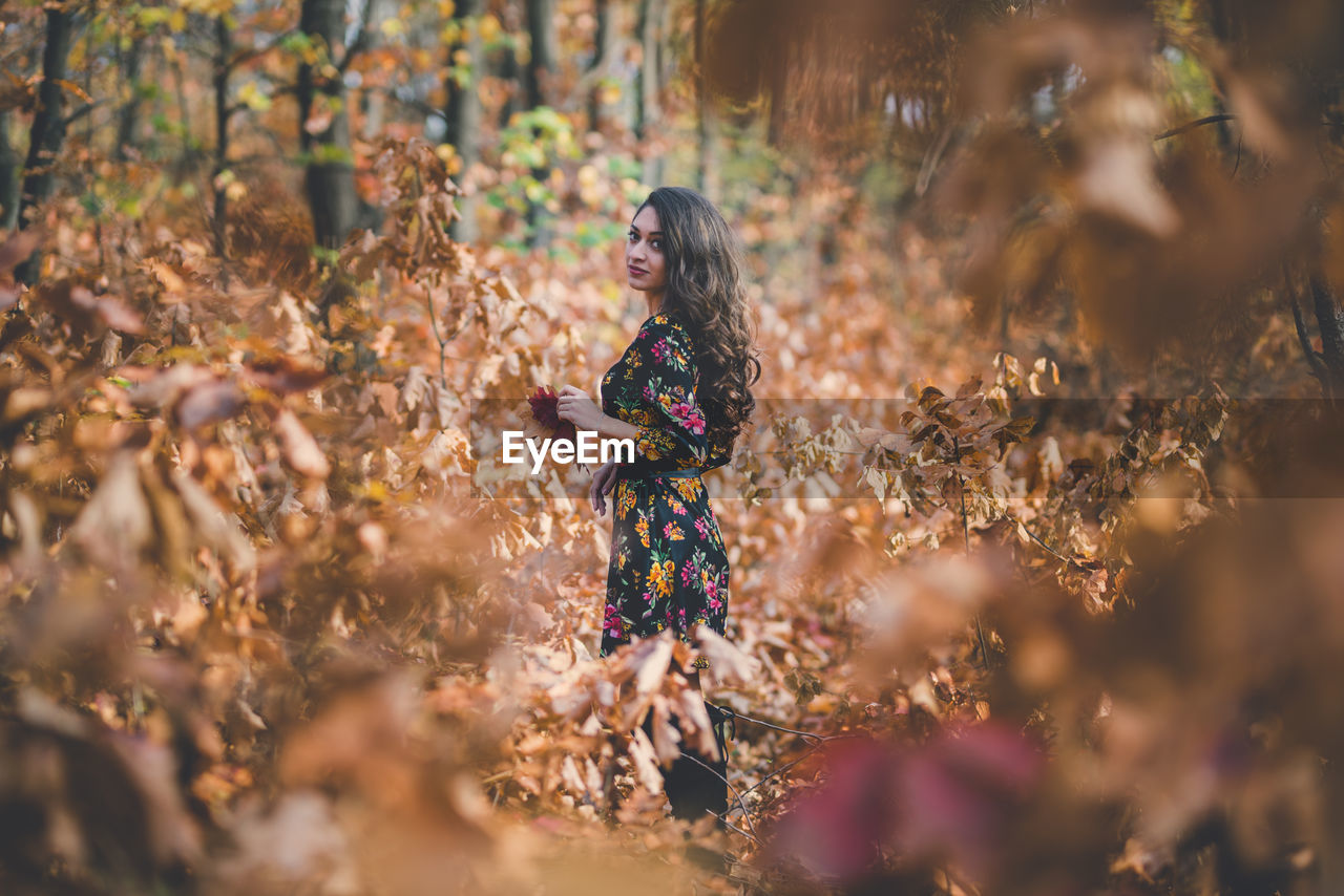 Woman standing amidst leaves on field