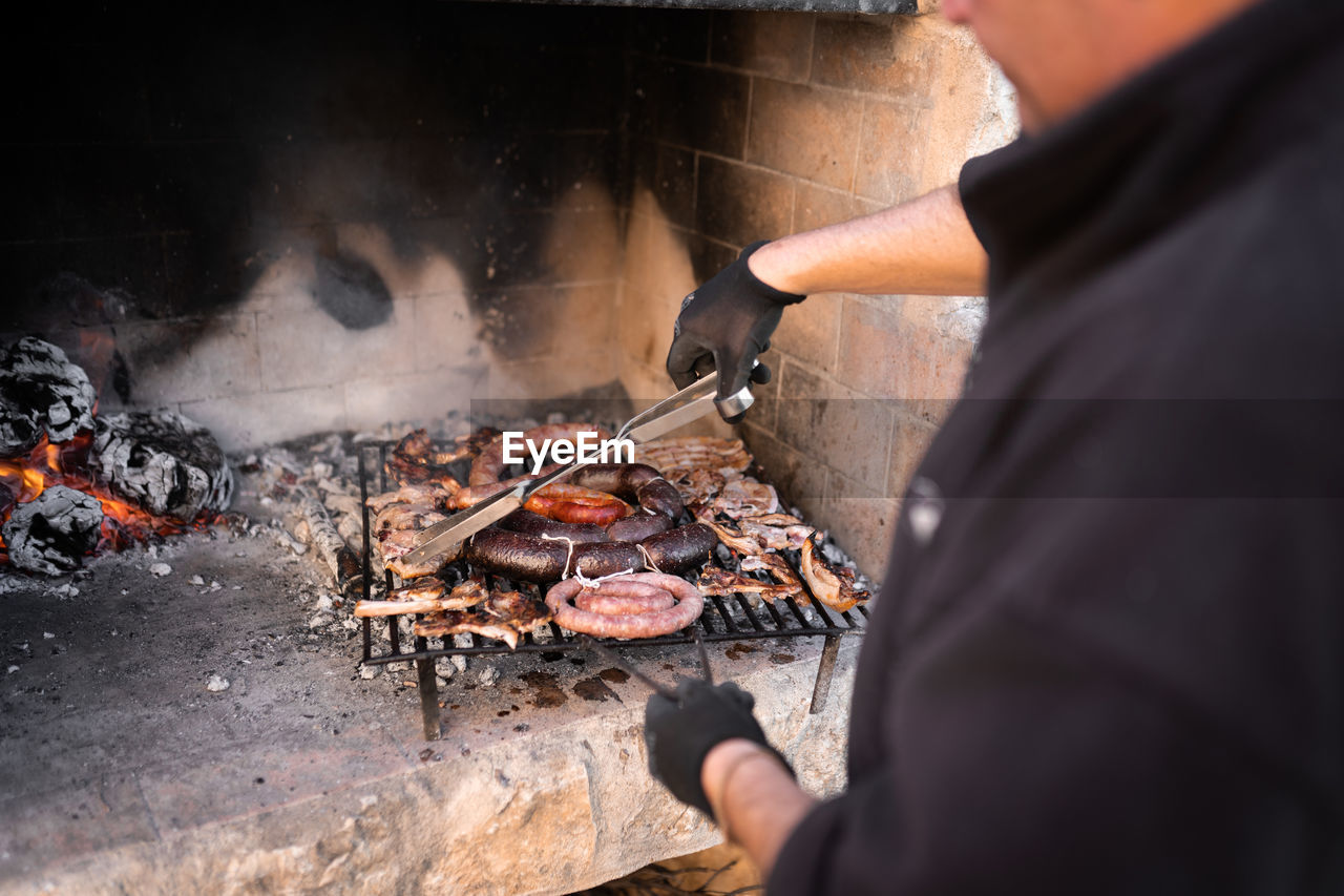 Man in his forties preparing a barbecue flipping the food with different types of meat