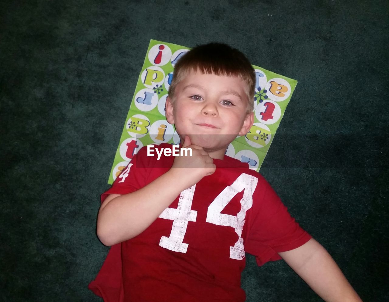 Portrait of smiling boy lying on paper