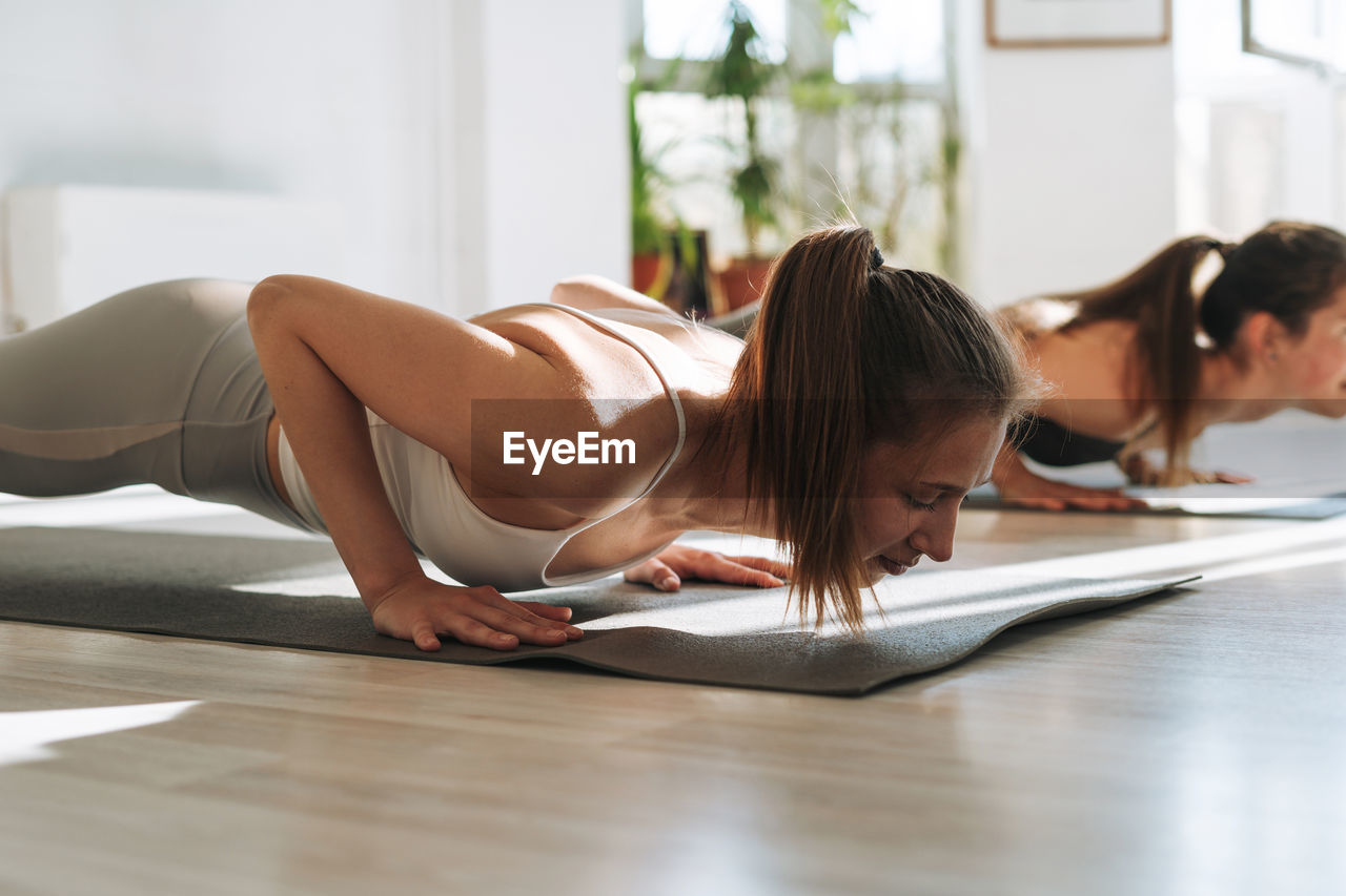 Young fit women practice yoga doing asana in bright yoga studio