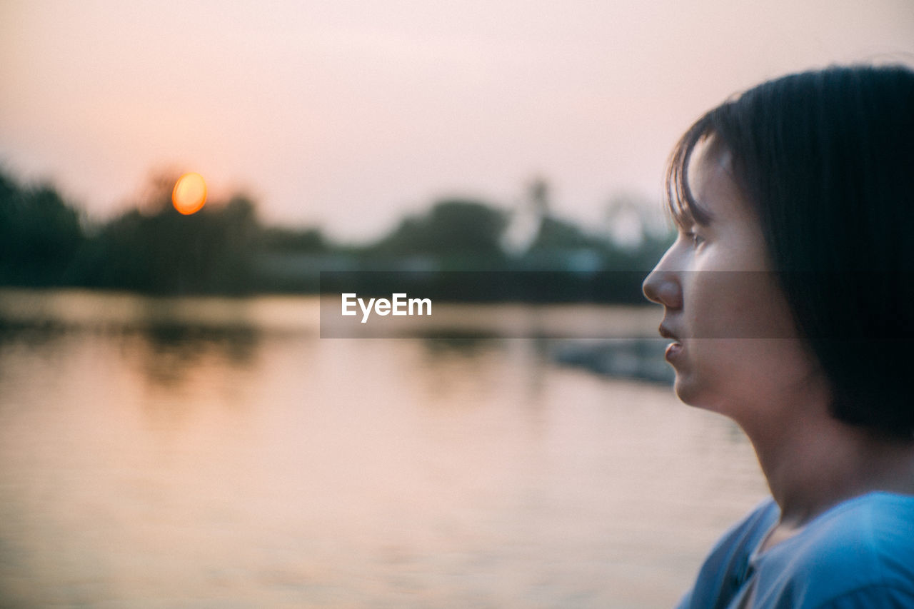 PORTRAIT OF MAN LOOKING AWAY AT LAKE