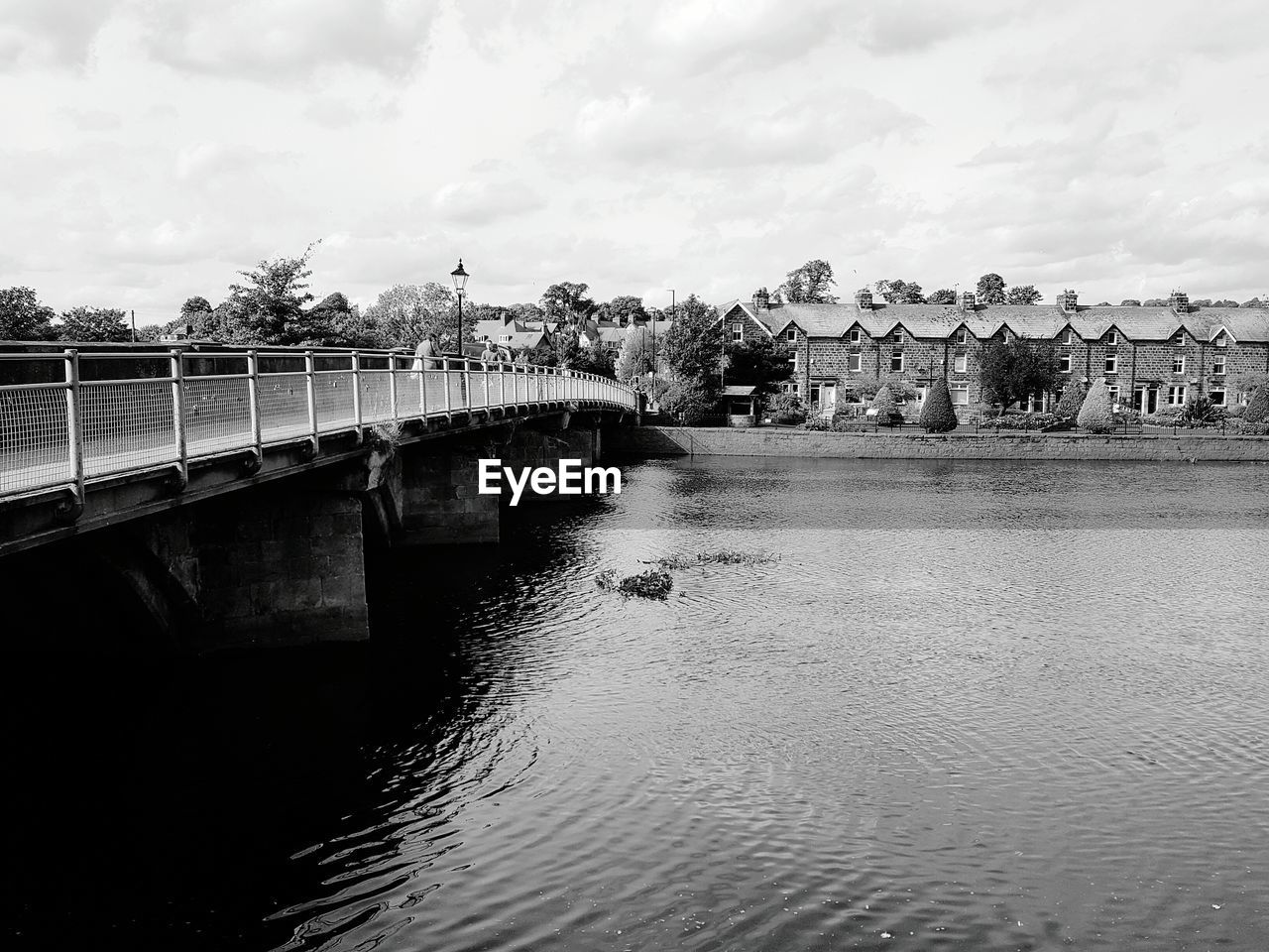 Bridge over river by buildings against sky