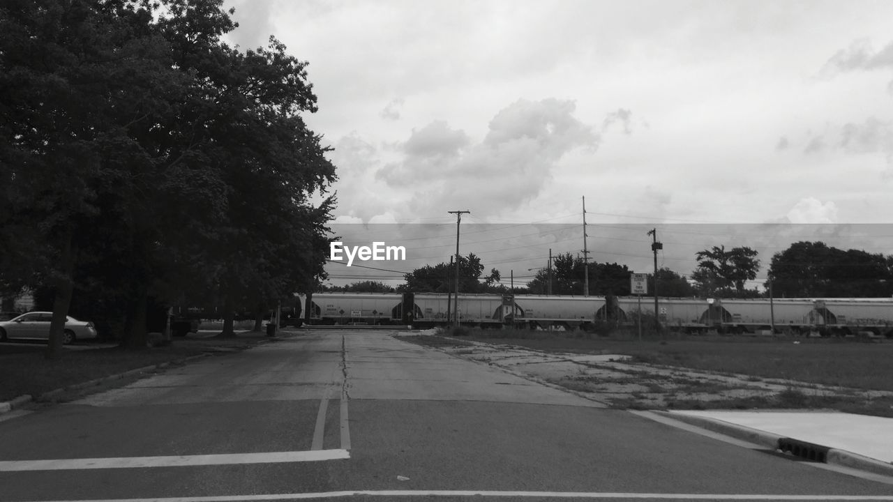 EMPTY ROAD WITH TREES IN BACKGROUND