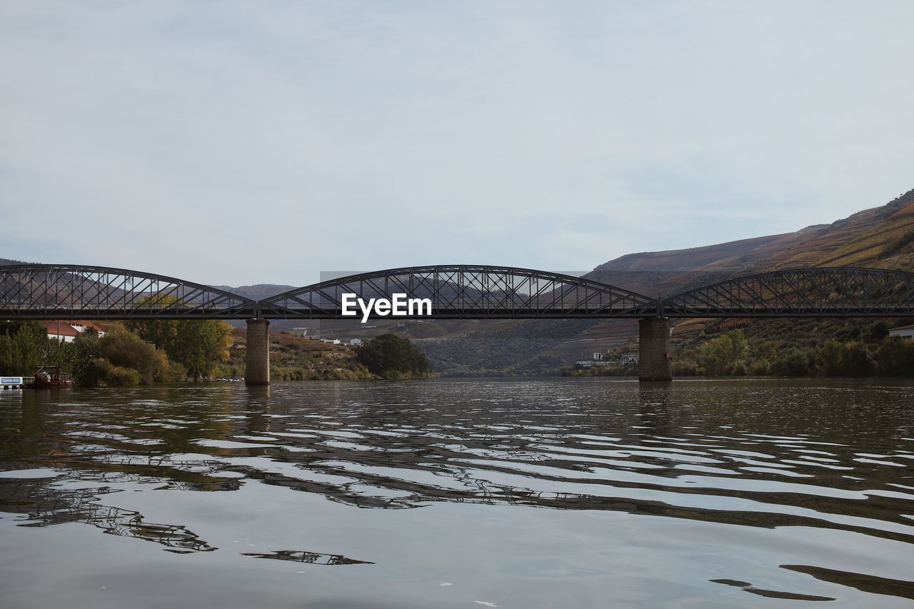 BRIDGE OVER RIVER AGAINST SKY SEEN THROUGH WET ARCH