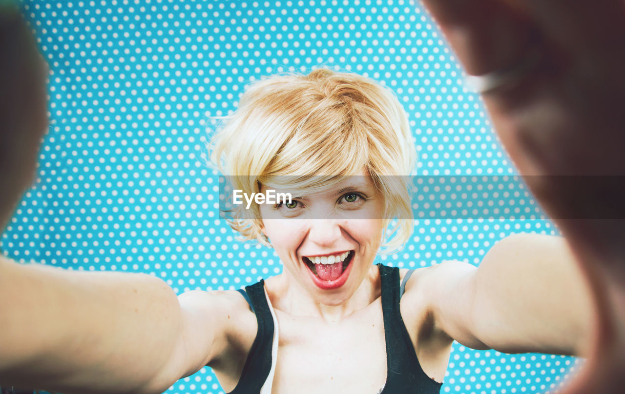 Portrait of smiling woman against blue curtain