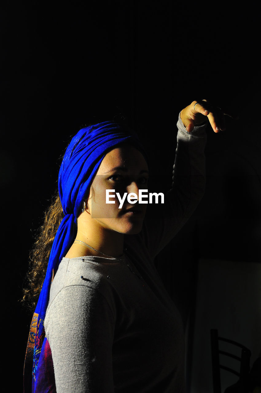 Woman wearing blue headwear against black background