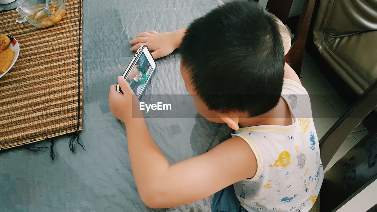 High angle view of boy using mobile phone at home