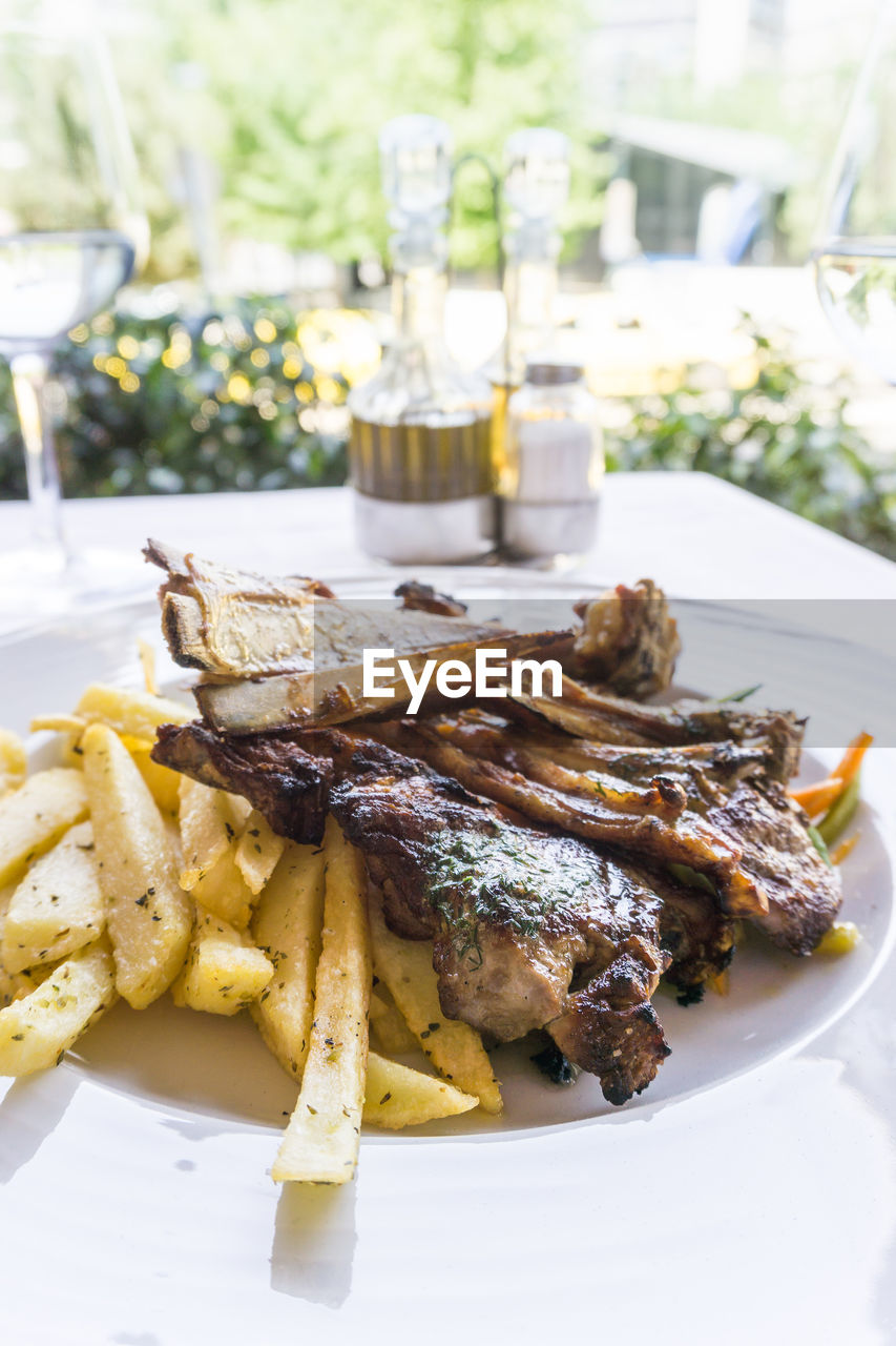 Close-up of lamb chops with french fries served in plate on table