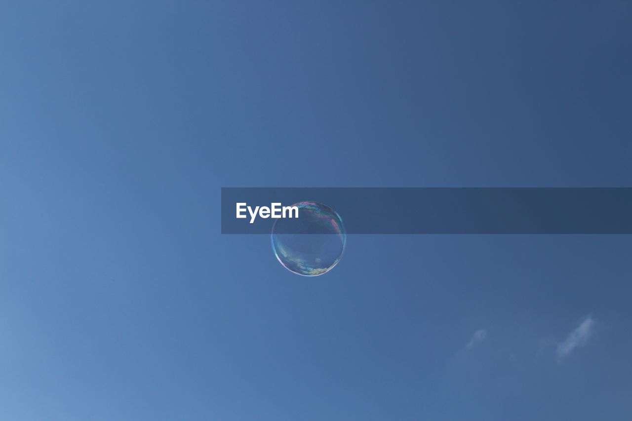 LOW ANGLE VIEW OF BUBBLE AGAINST CLEAR BLUE SKY