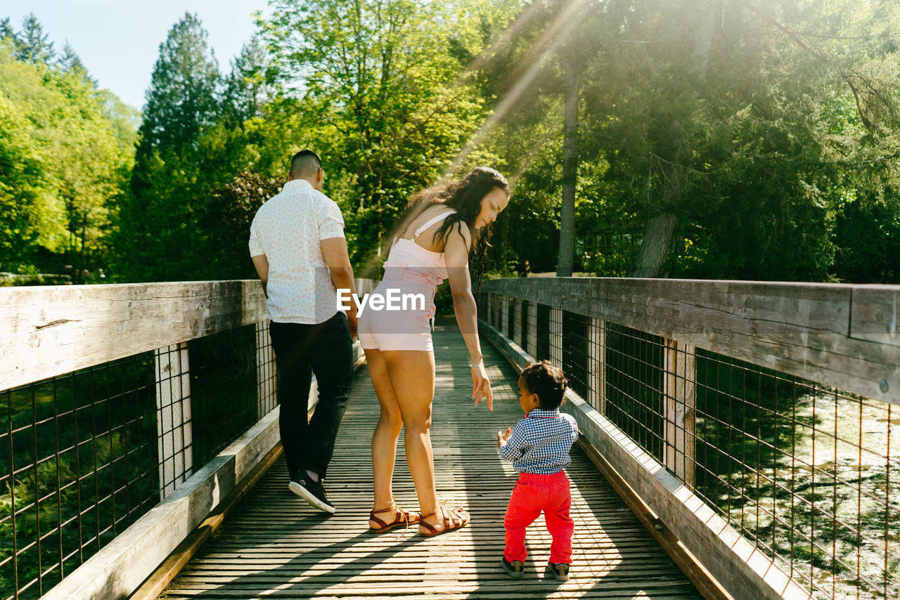 View from behind of a family walking on a bridge with sun flare