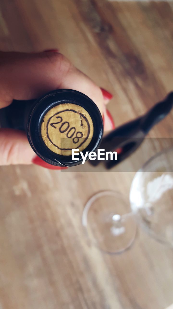 Cropped hand of woman holding wine bottle with number on cork