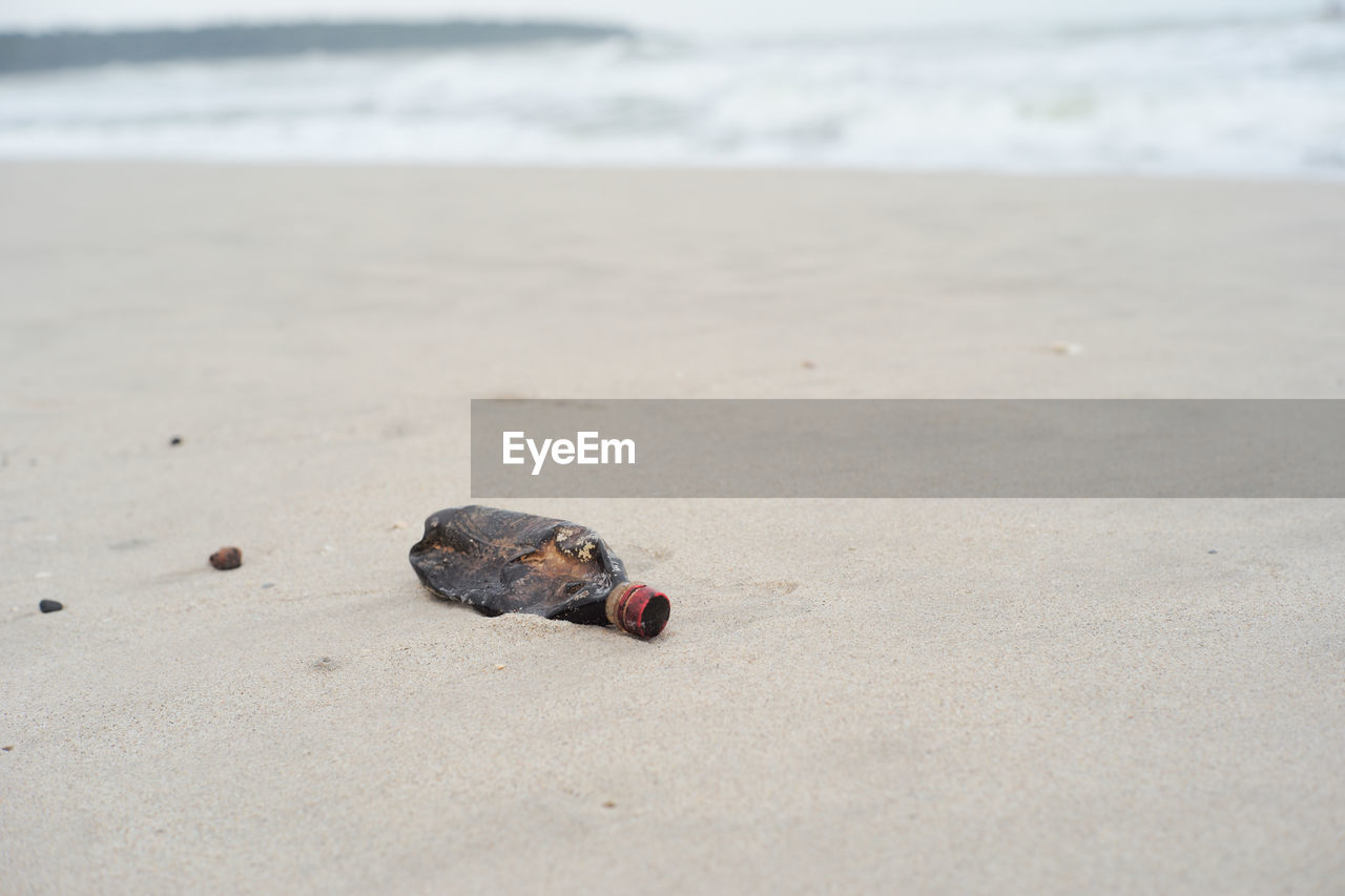 Selective focus on the plastic bottle on the beach with blurred seascape in background. trash