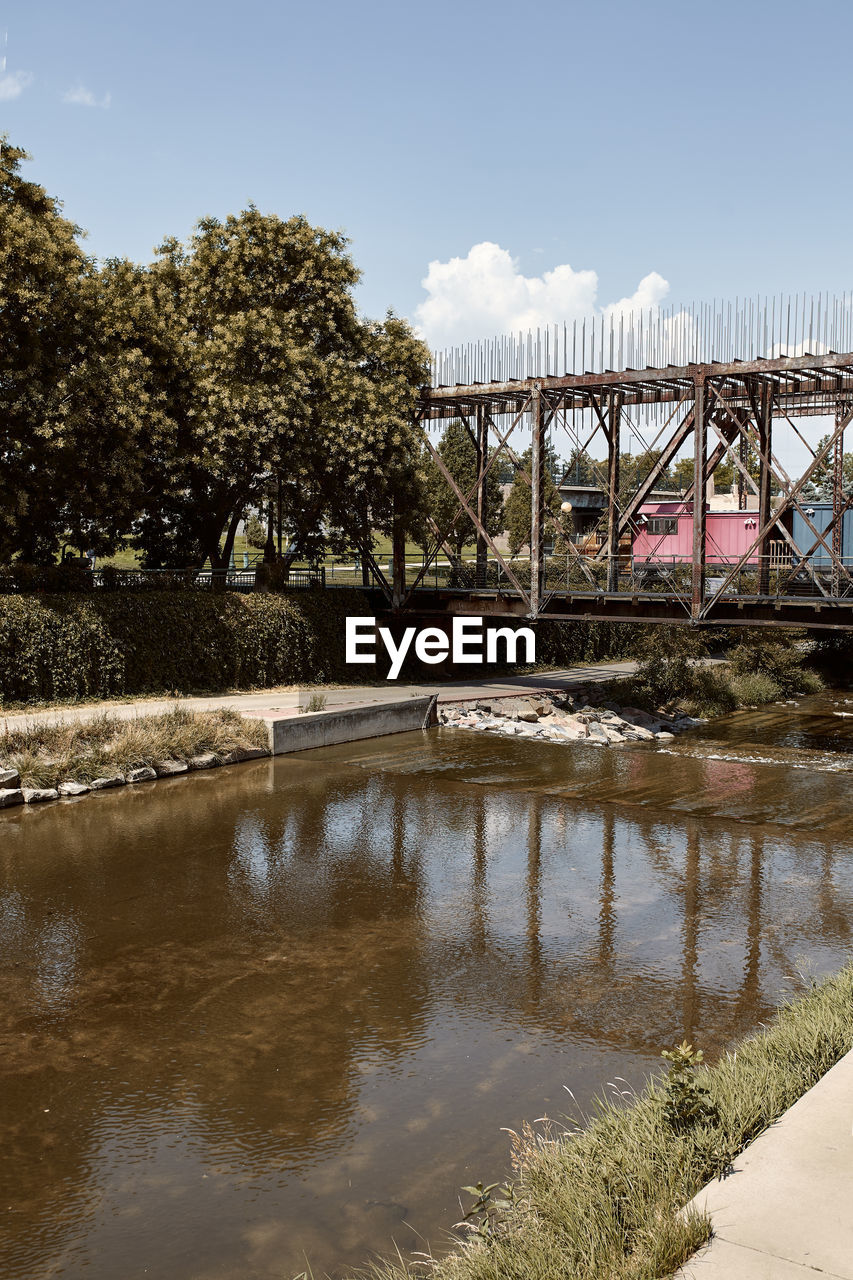 BRIDGE OVER RIVER BY TREES AGAINST SKY