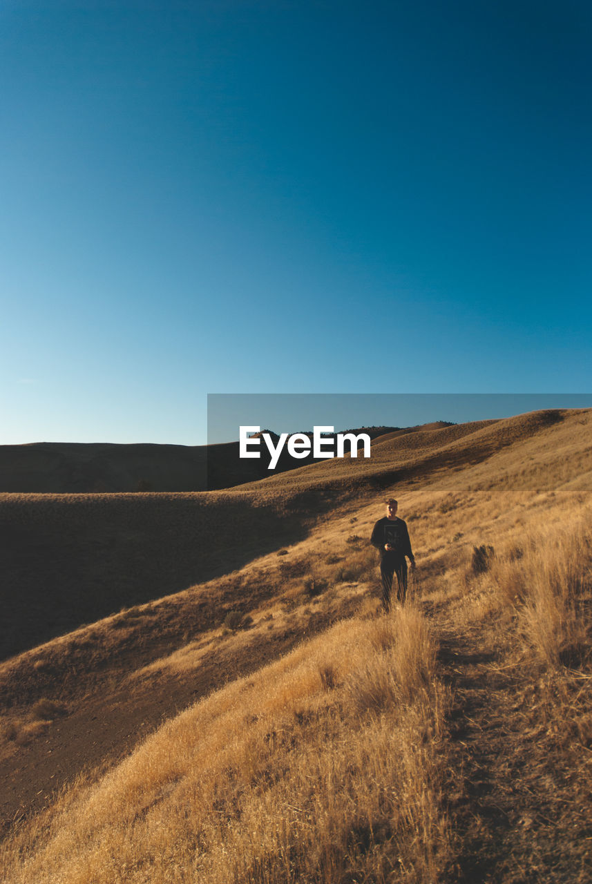 Man standing at desert against clear sky