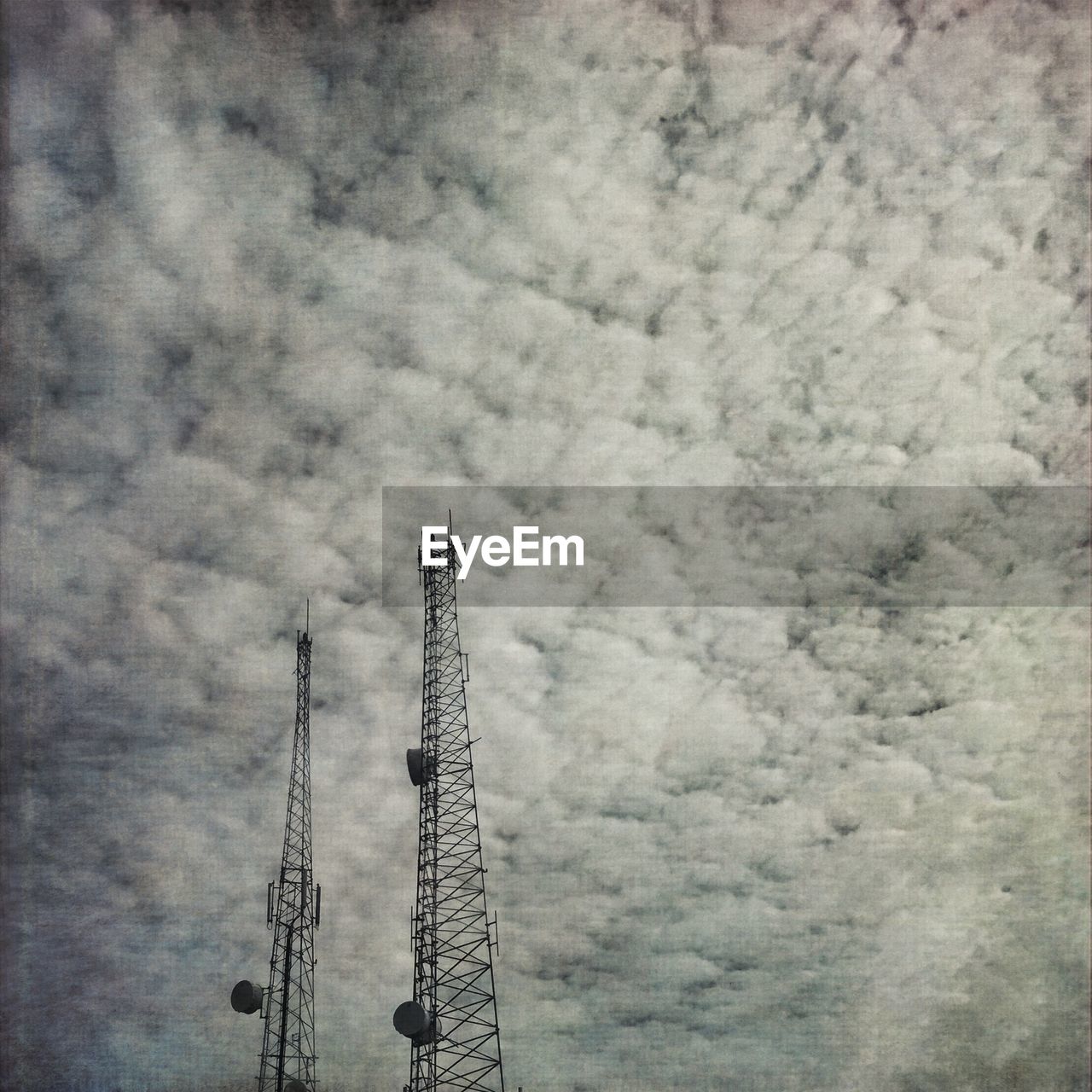 Low angle view of communications towers against sky