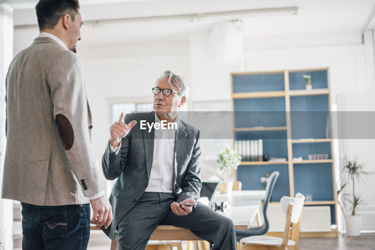 Senior businessman talking to young businessman in office