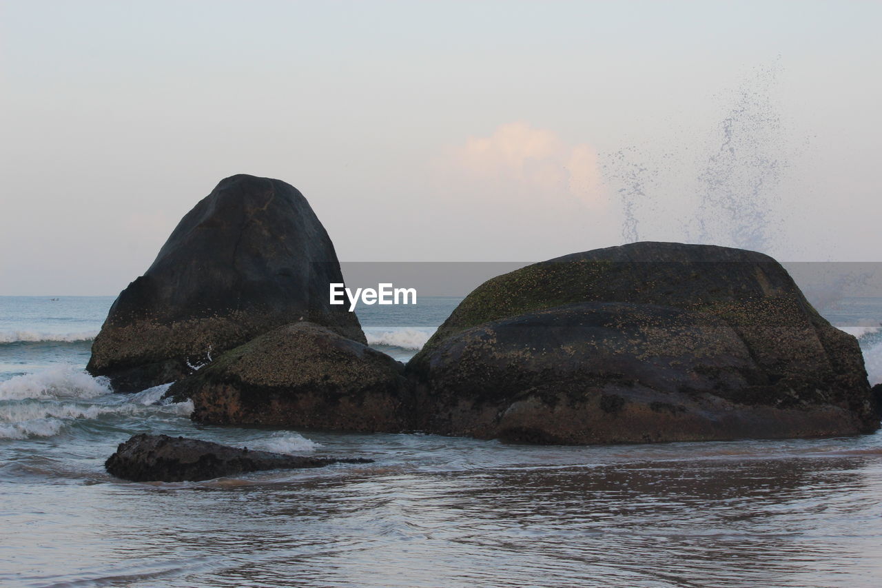 Rock formation in sea against sky