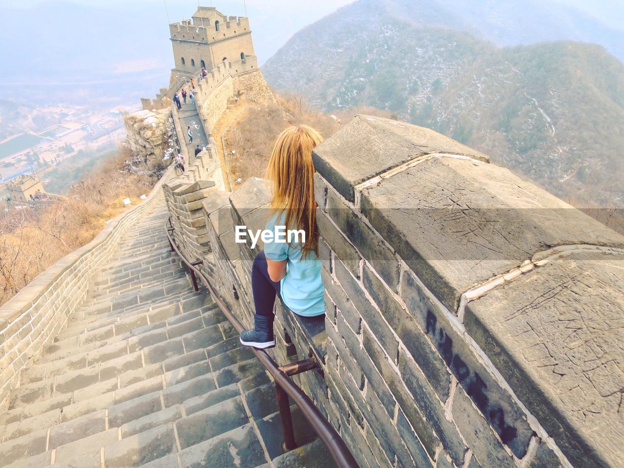 Rear view of woman sitting at great wall of china
