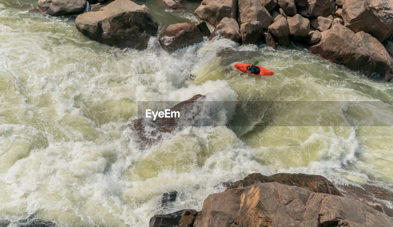 HIGH ANGLE VIEW OF WATER FLOWING THROUGH ROCKS IN RIVER