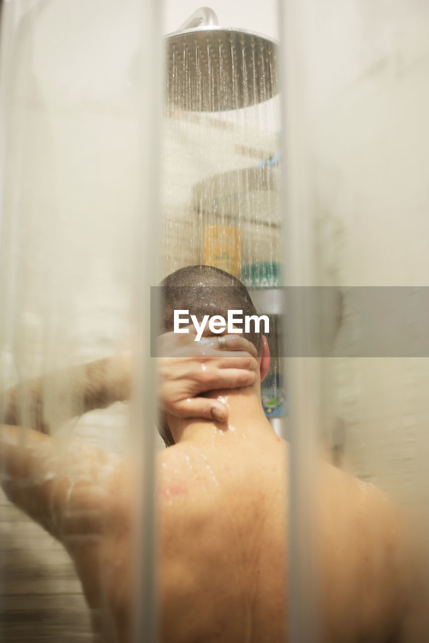 Rear view of mature man bathing in bathroom