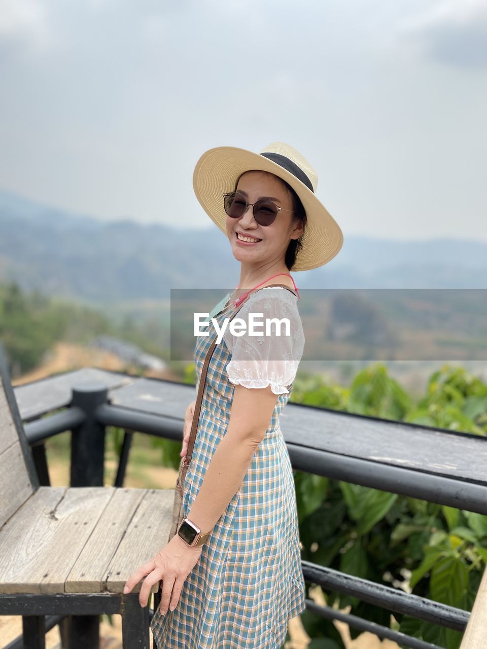 Portrait of woman standing by railing against mountain