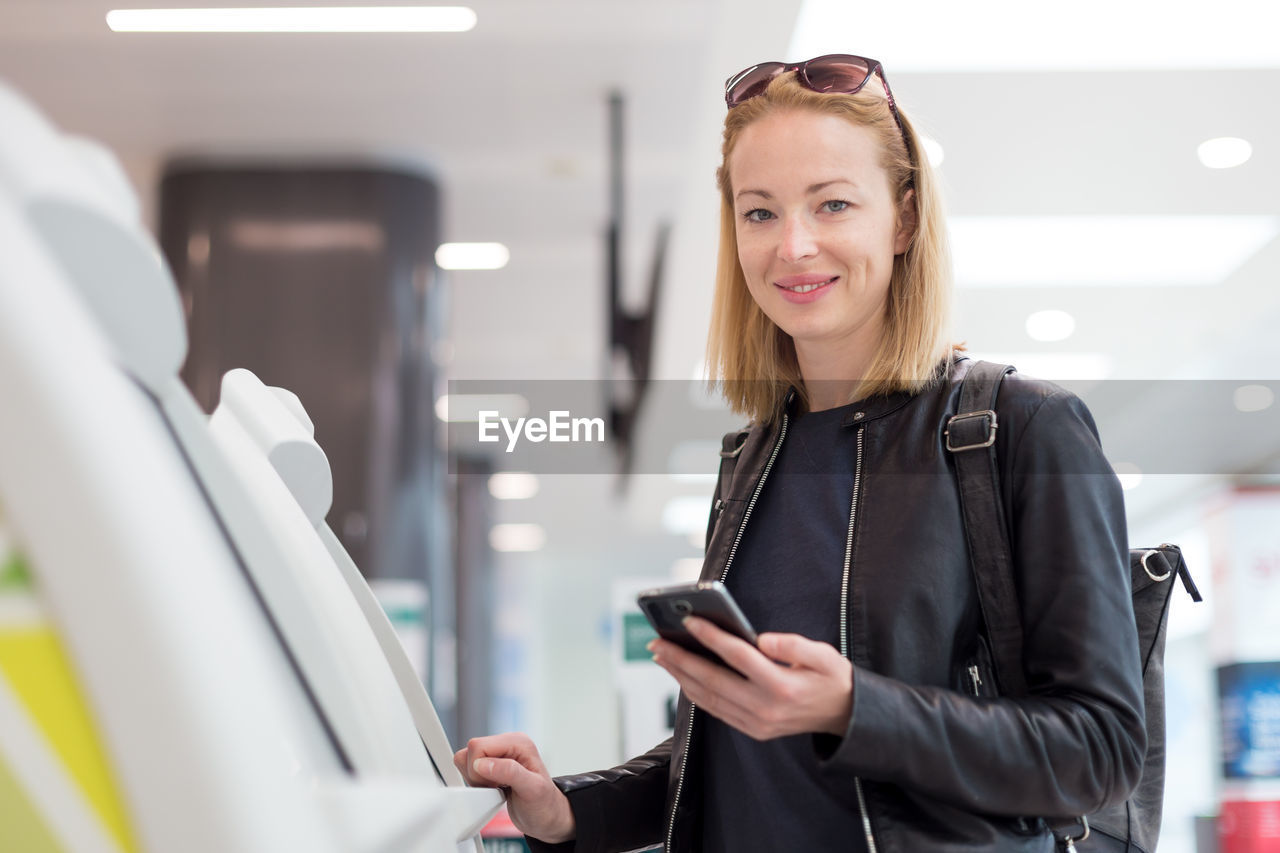 Portrait of beautiful woman using atm at airport