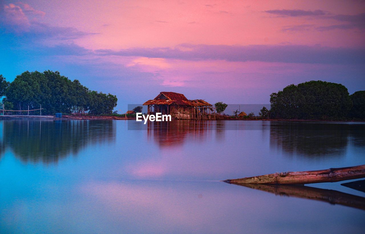 LAKE BY BUILDING AGAINST SKY DURING SUNSET